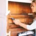 The woman is painting the furniture.